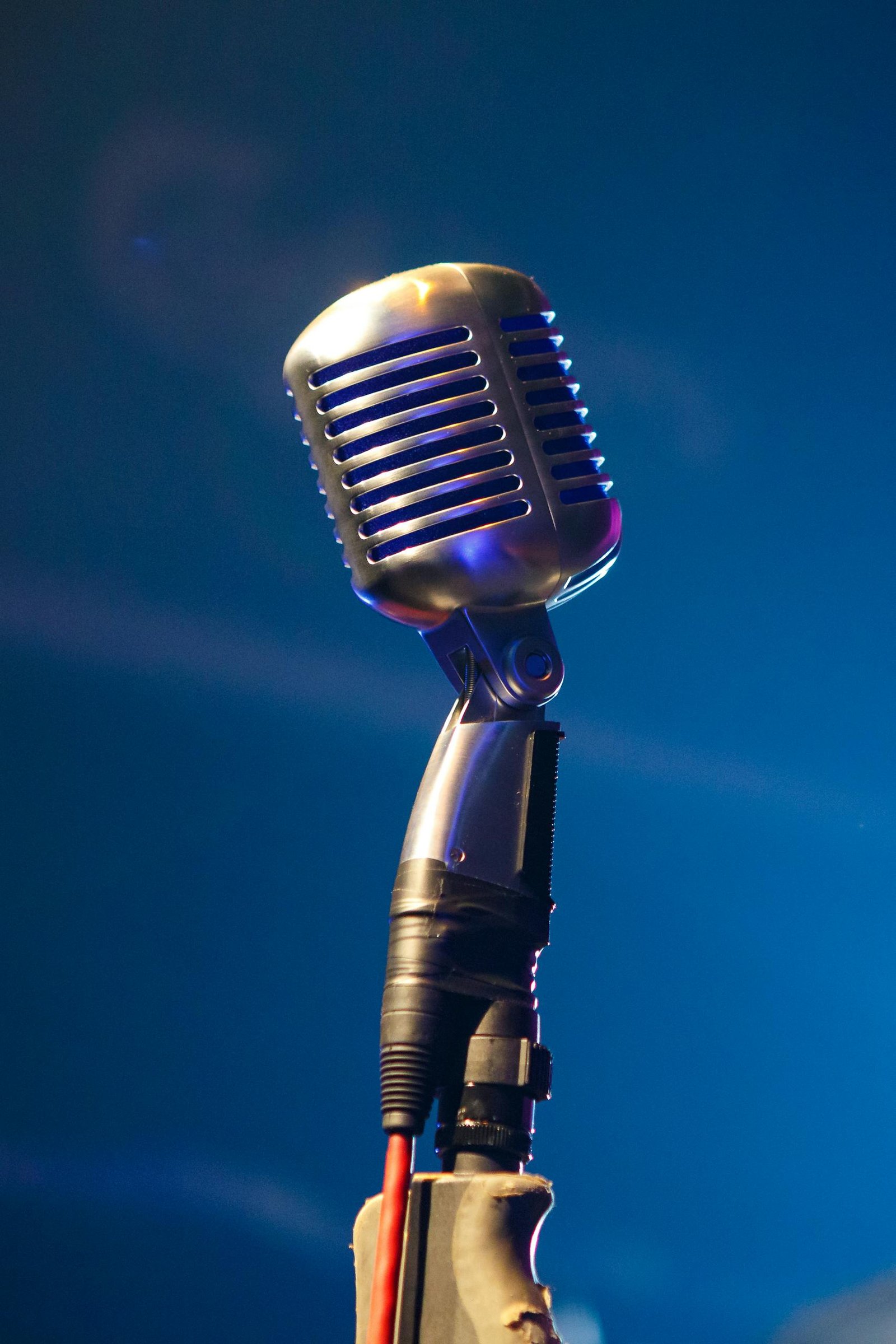 Retro microphone on stage with blue lighting creates a nostalgic musical vibe.